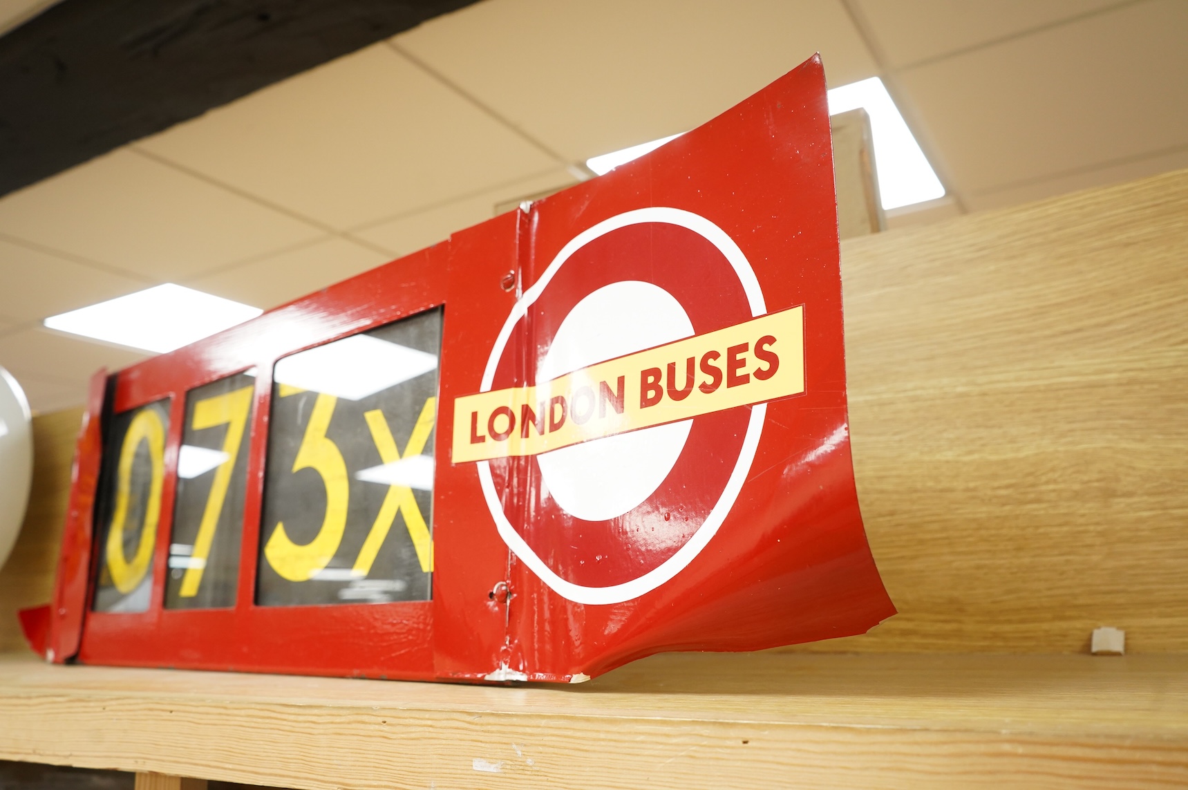 A London Transport bus destination blind box, complete with mechanism and three numerical destination blinds, with later applied sheets of red painted steel bolted to each side, mechanism with winding handle and row sele